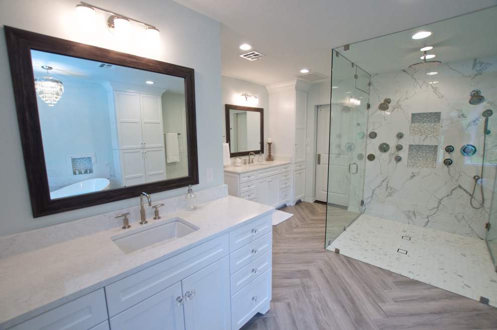 Idéer för att renovera ett stort funkis vit vitt en-suite badrum, med skåp i shakerstil, vita skåp, ett fristående badkar, en kantlös dusch, en toalettstol med separat cisternkåpa, vit kakel, porslinskakel, vita väggar, klinkergolv i porslin, ett undermonterad handfat, bänkskiva i kvarts, brunt golv och dusch med gångjärnsdörr