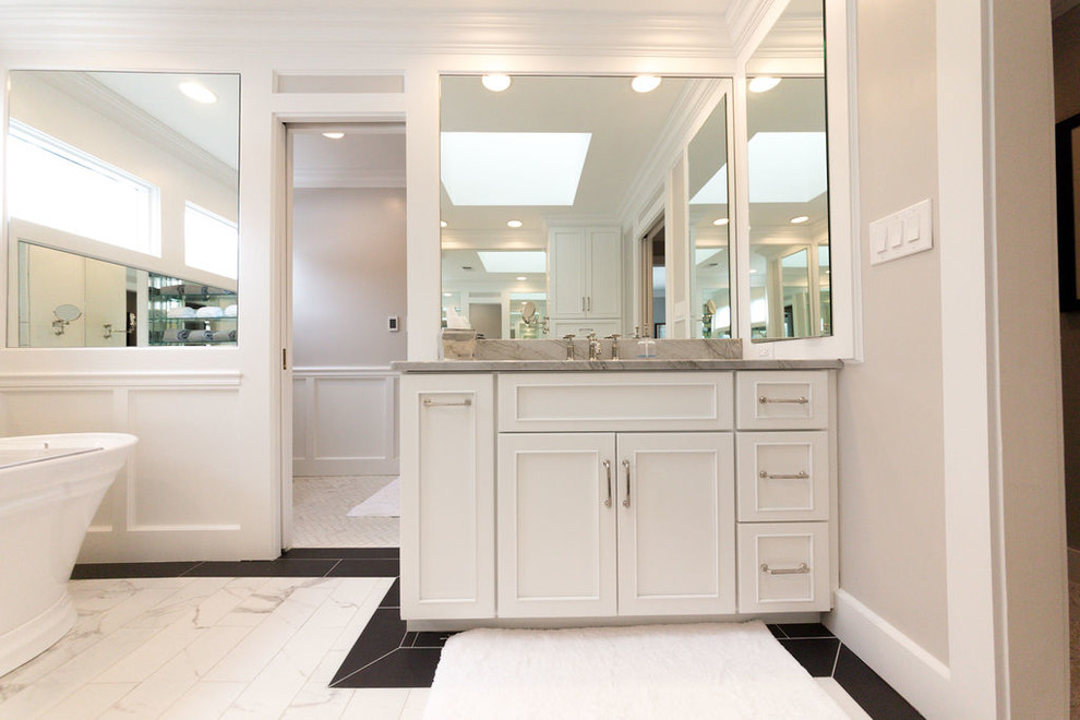 Modern inredning av ett stort beige beige en-suite badrum, med luckor med infälld panel, vita skåp, ett fristående badkar, en kantlös dusch, en toalettstol med separat cisternkåpa, vit kakel, marmorkakel, beige väggar, marmorgolv, ett undermonterad handfat, bänkskiva i kvartsit, vitt golv och med dusch som är öppen