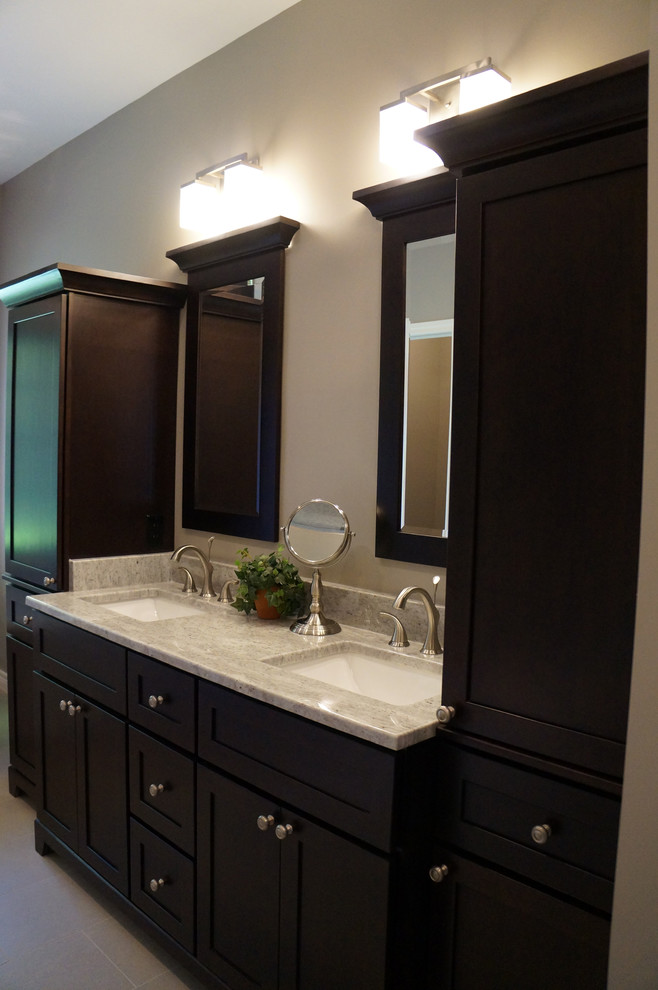 Large contemporary ensuite bathroom in Toronto with recessed-panel cabinets, dark wood cabinets, a freestanding bath, an alcove shower, a two-piece toilet, grey tiles, stone tiles, beige walls, porcelain flooring, a submerged sink and granite worktops.