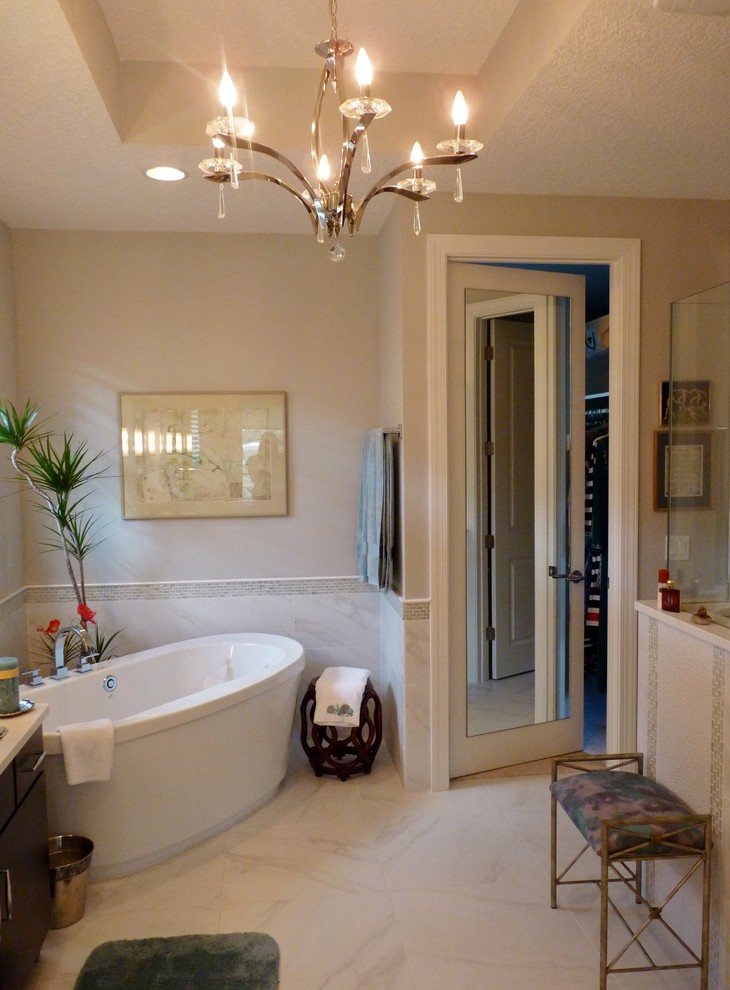 Photo of a large traditional ensuite bathroom in Jacksonville with a vessel sink, flat-panel cabinets, dark wood cabinets, a freestanding bath, beige walls and marble flooring.