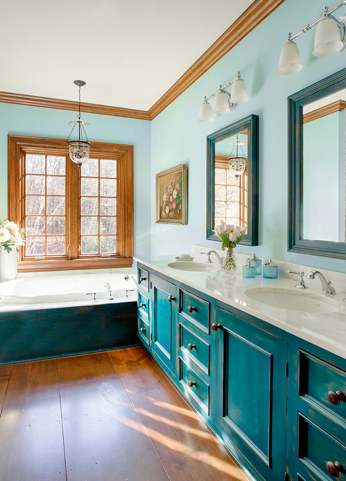 Immagine di una stanza da bagno padronale classica con pareti blu, pavimento in legno massello medio, lavabo sottopiano, ante blu e ante con riquadro incassato