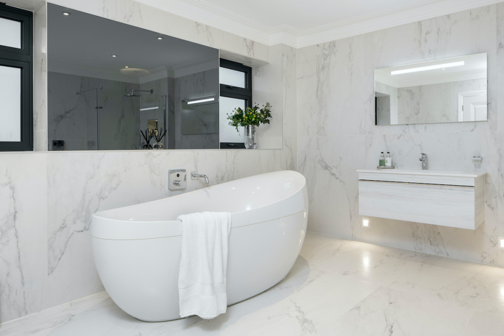 Design ideas for a medium sized contemporary family bathroom in Essex with flat-panel cabinets, white cabinets, a freestanding bath, a built-in shower, white tiles, marble tiles, marble flooring, a wall-mounted sink, white floors and an open shower.