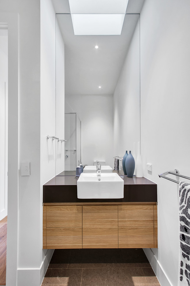 Idée de décoration pour une salle de bain design en bois brun avec un placard à porte plane, un carrelage blanc, un mur blanc, une vasque, un plan de toilette en quartz, un plan de toilette marron et un sol gris.