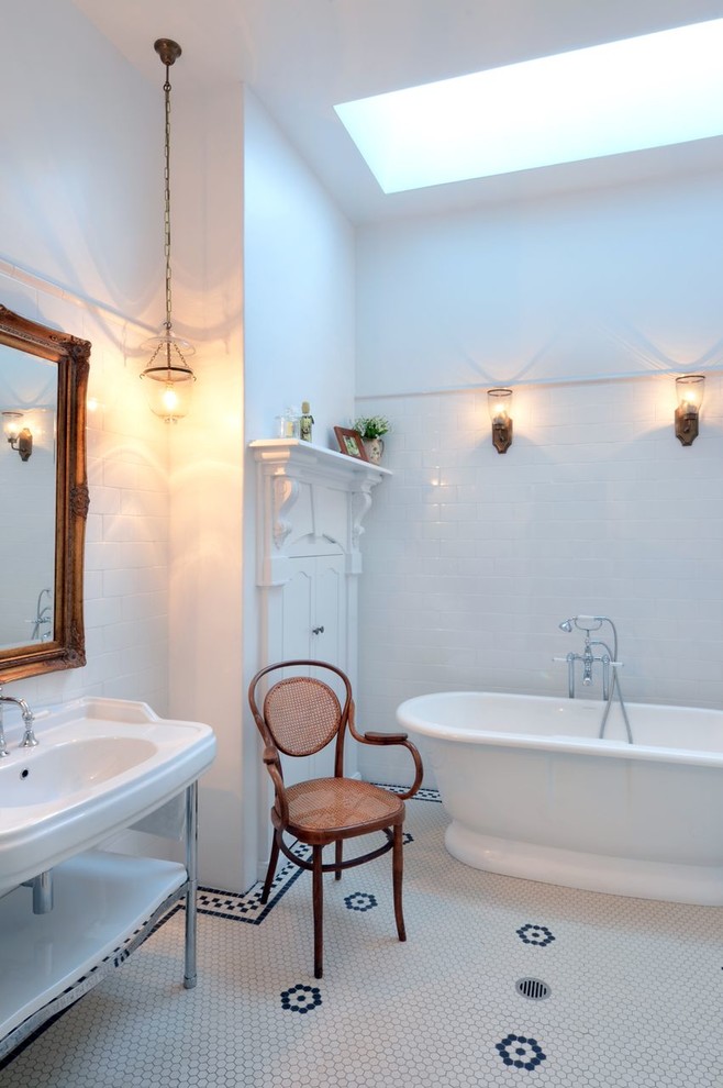На фото: ванная комната в викторианском стиле с консольной раковиной, отдельно стоящей ванной, белой плиткой, белыми стенами и полом из мозаичной плитки