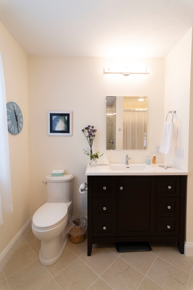 Alcove shower - mid-sized transitional 3/4 beige tile and ceramic tile ceramic tile and beige floor alcove shower idea in Boston with black cabinets, a one-piece toilet, beige walls, an integrated sink, solid surface countertops, a hinged shower door and white countertops