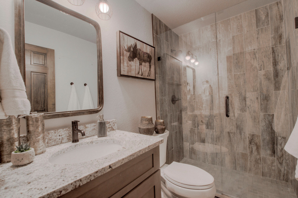 Inspiration för ett lantligt beige beige badrum med dusch, med skåp i shakerstil, grå skåp, en toalettstol med separat cisternkåpa, grå kakel, porslinskakel, grå väggar, klinkergolv i porslin, ett undermonterad handfat, granitbänkskiva, grått golv och dusch med gångjärnsdörr