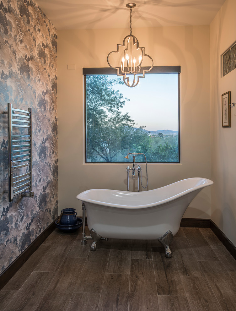 Cette photo montre une salle de bain principale nature de taille moyenne avec un placard avec porte à panneau surélevé, des portes de placard bleues, un mur multicolore, un sol en vinyl, un lavabo posé, un sol marron, un plan de toilette gris et une baignoire sur pieds.