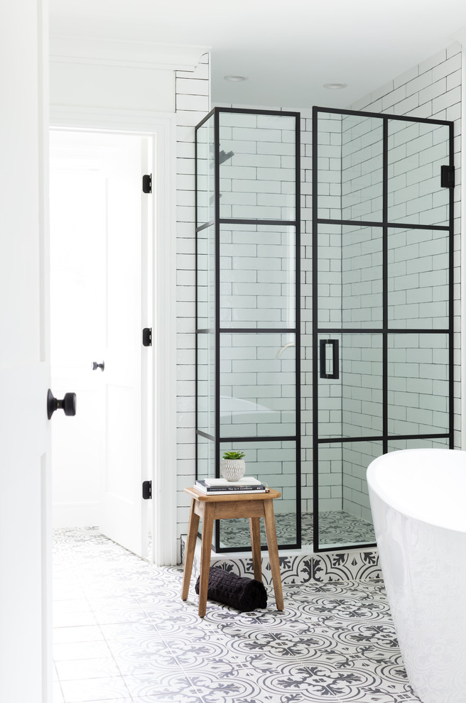 На фото: главная ванная комната в стиле кантри с отдельно стоящей ванной, угловым душем, белой плиткой, плиткой кабанчик, белыми стенами, разноцветным полом и душем с распашными дверями с