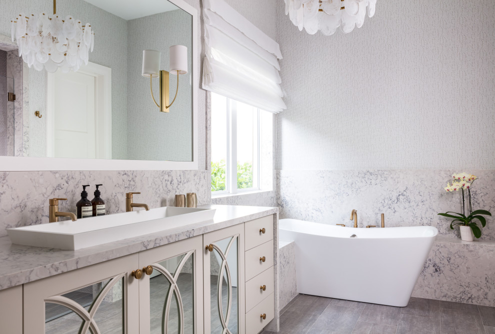 Exempel på ett modernt flerfärgad flerfärgat en-suite badrum, med beige skåp, ett fristående badkar, flerfärgad kakel, stenhäll, ett avlångt handfat och luckor med infälld panel