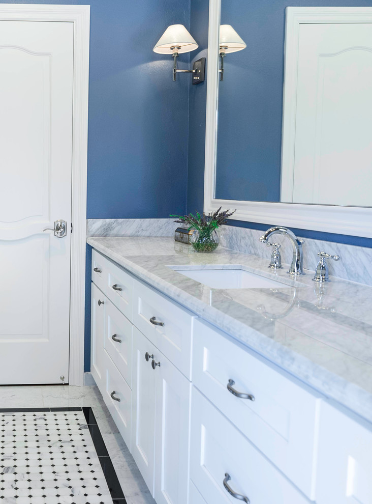 Modern inredning av ett mellanstort badrum, med luckor med infälld panel, vita skåp, en hörndusch, en toalettstol med hel cisternkåpa, svart och vit kakel, stenkakel, blå väggar, marmorgolv, ett nedsänkt handfat och marmorbänkskiva