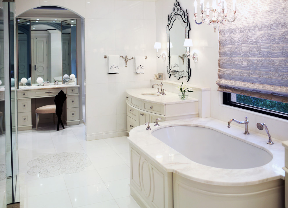 Modern inredning av ett stort en-suite badrum, med ett undermonterad handfat, skåp i shakerstil, vita skåp, marmorbänkskiva, ett fristående badkar, vit kakel, keramikplattor, vita väggar, klinkergolv i keramik och en dusch i en alkov