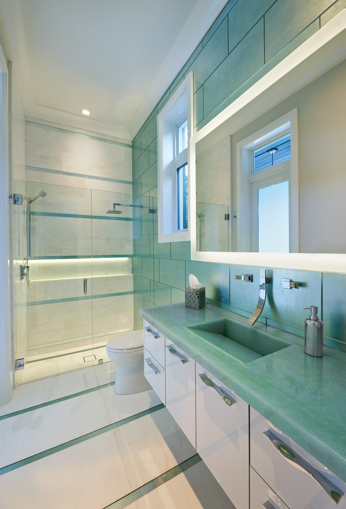マイアミにある高級な広いコンテンポラリースタイルのおしゃれなバスルーム (浴槽なし) (フラットパネル扉のキャビネット、白いキャビネット、アルコーブ型シャワー、一体型トイレ	、緑のタイル、ガラスタイル、緑の壁、大理石の床、一体型シンク、ガラスの洗面台、ターコイズの洗面カウンター) の写真
