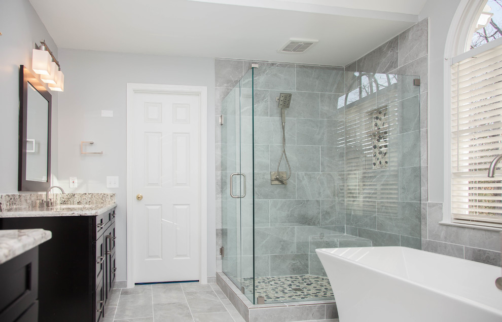 Mid-sized trendy master gray tile and porcelain tile porcelain tile and gray floor bathroom photo in Atlanta with shaker cabinets, dark wood cabinets, a two-piece toilet, gray walls, an undermount sink, granite countertops and a hinged shower door