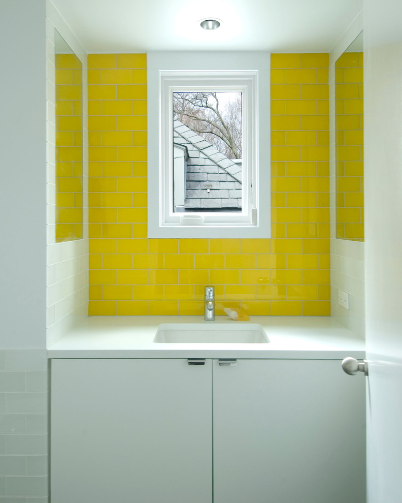 This is an example of a contemporary bathroom in New York with a submerged sink, flat-panel cabinets, white cabinets, solid surface worktops, yellow tiles and metro tiles.