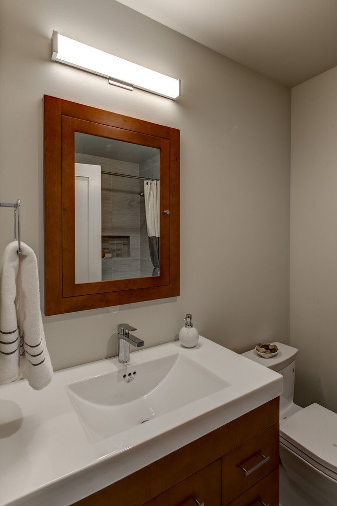 Idée de décoration pour une petite salle de bain craftsman en bois brun avec un lavabo intégré, un placard à porte plane, WC à poser et un mur beige.