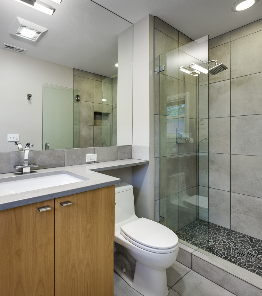 На фото: ванная комната: освещение в современном стиле с врезной раковиной, плоскими фасадами, светлыми деревянными фасадами, столешницей из искусственного кварца, открытым душем, серой плиткой, керамогранитной плиткой и открытым душем