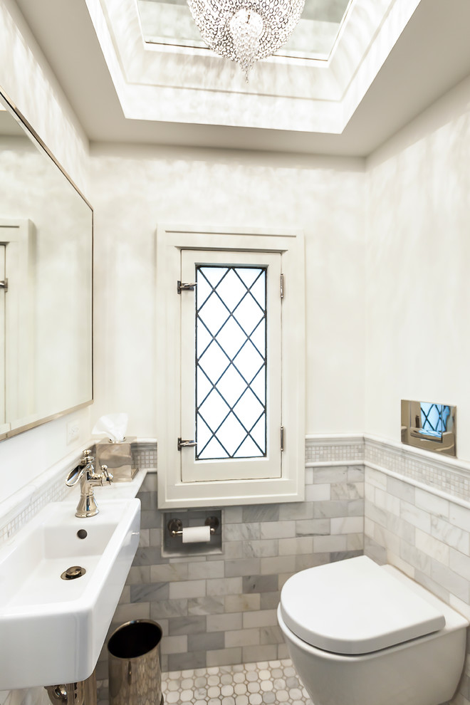 Modelo de cuarto de baño actual pequeño con lavabo suspendido, sanitario de pared, baldosas y/o azulejos grises, baldosas y/o azulejos de piedra y paredes blancas