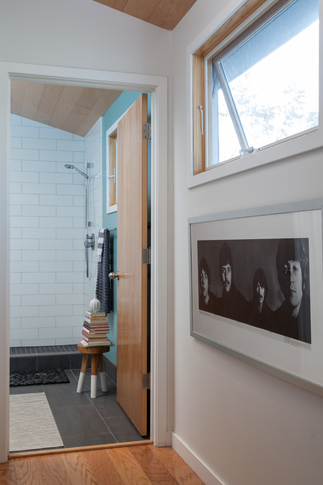 Idée de décoration pour une salle de bain principale minimaliste en bois clair de taille moyenne avec un placard à porte plane, une douche ouverte, WC à poser, un carrelage blanc, des carreaux de céramique, un mur bleu, un sol en carrelage de porcelaine, un plan vasque et un plan de toilette en quartz modifié.