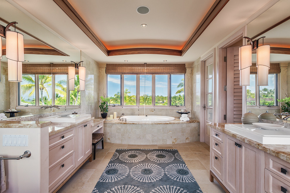 Foto di una grande stanza da bagno padronale tropicale con top in granito, vasca da incasso e pavimento in pietra calcarea