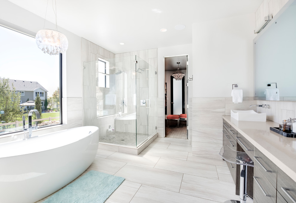 Пример оригинального дизайна: ванная комната в современном стиле с плоскими фасадами, серыми фасадами, отдельно стоящей ванной, угловым душем, серой плиткой, белыми стенами, настольной раковиной, серым полом, душем с распашными дверями и бежевой столешницей