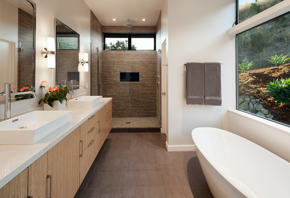 Inredning av ett modernt en-suite badrum, med släta luckor, skåp i ljust trä, ett fristående badkar, en dusch i en alkov, brun kakel, stenkakel, vita väggar, klinkergolv i porslin, ett fristående handfat, bänkskiva i kvarts och dusch med gångjärnsdörr