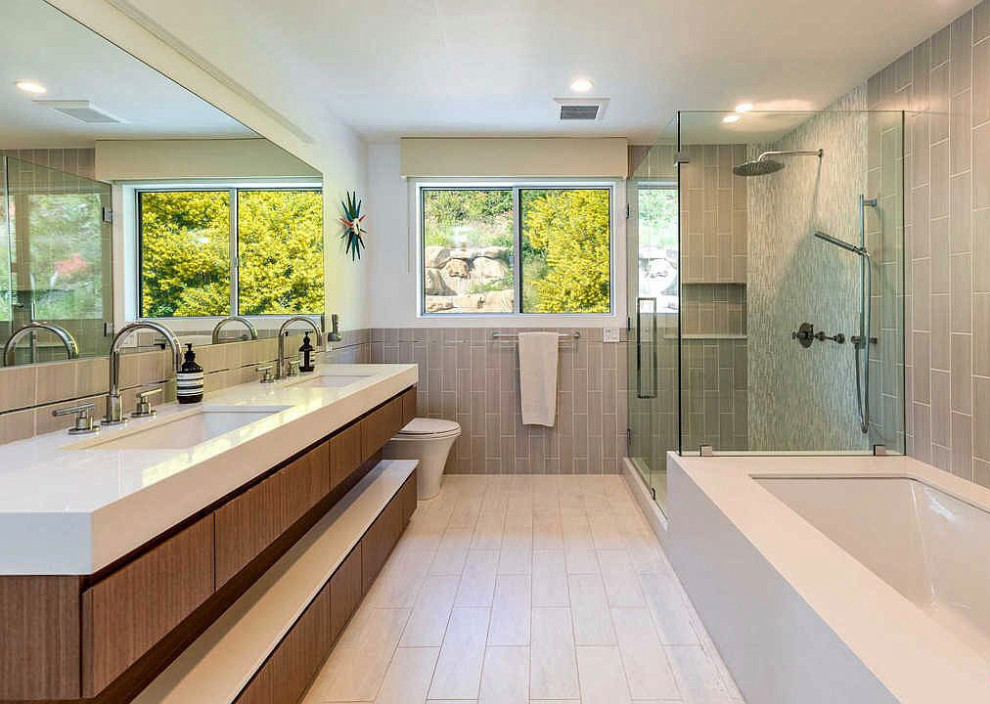 Example of a large trendy kids' gray tile and porcelain tile porcelain tile, white floor and double-sink corner shower design in Los Angeles with flat-panel cabinets, brown cabinets, an undermount tub, a one-piece toilet, white walls, an undermount sink, terrazzo countertops, a hinged shower door, white countertops, a niche and a built-in vanity