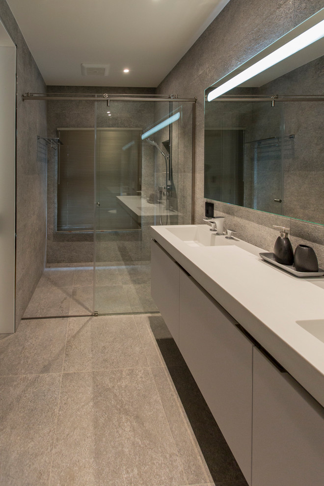 Bathroom - mid-sized contemporary master gray tile and cement tile concrete floor and gray floor bathroom idea in San Francisco with flat-panel cabinets, white cabinets, a wall-mount toilet, gray walls, an integrated sink, solid surface countertops and white countertops