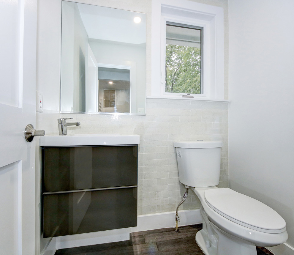 Foto på ett mellanstort funkis vit badrum med dusch, med släta luckor, en toalettstol med hel cisternkåpa, keramikplattor, vita väggar, ett integrerad handfat, bänkskiva i akrylsten, grå skåp, beige kakel, bambugolv och brunt golv