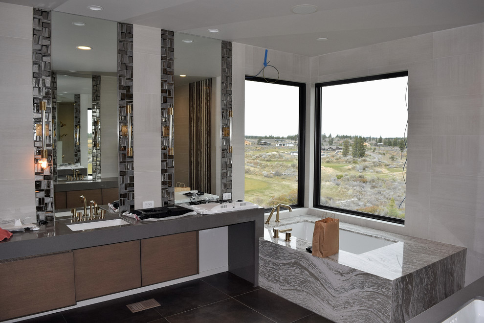 Exempel på ett stort modernt grå grått en-suite badrum, med släta luckor, bruna skåp, ett hörnbadkar, en öppen dusch, en toalettstol med hel cisternkåpa, grå kakel, glaskakel, grå väggar, klinkergolv i keramik, ett undermonterad handfat, granitbänkskiva, brunt golv och med dusch som är öppen