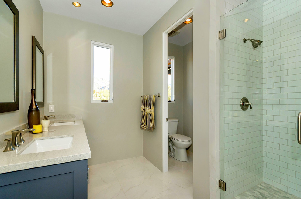 Aménagement d'une douche en alcôve contemporaine de taille moyenne avec un placard à porte shaker, des portes de placard bleues, WC séparés, un carrelage blanc, un carrelage métro, un mur beige, un sol en marbre, un lavabo encastré et un plan de toilette en verre recyclé.
