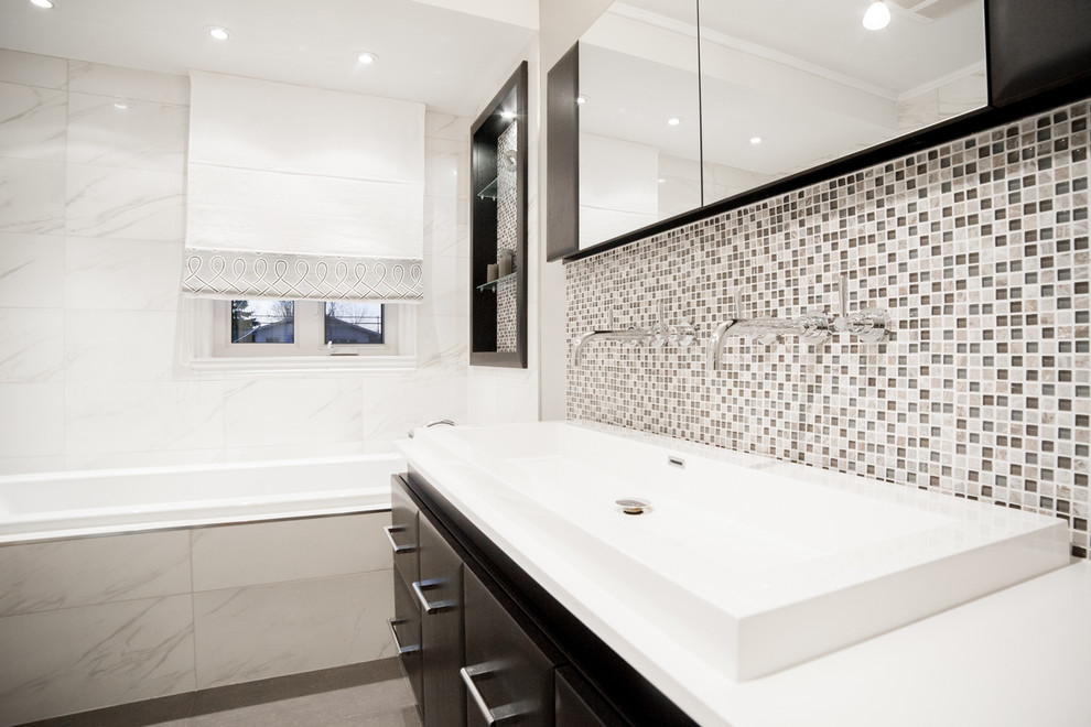 Bild på ett stort funkis en-suite badrum, med släta luckor, skåp i mörkt trä, ett platsbyggt badkar, marmorkakel, ett avlångt handfat och bänkskiva i akrylsten