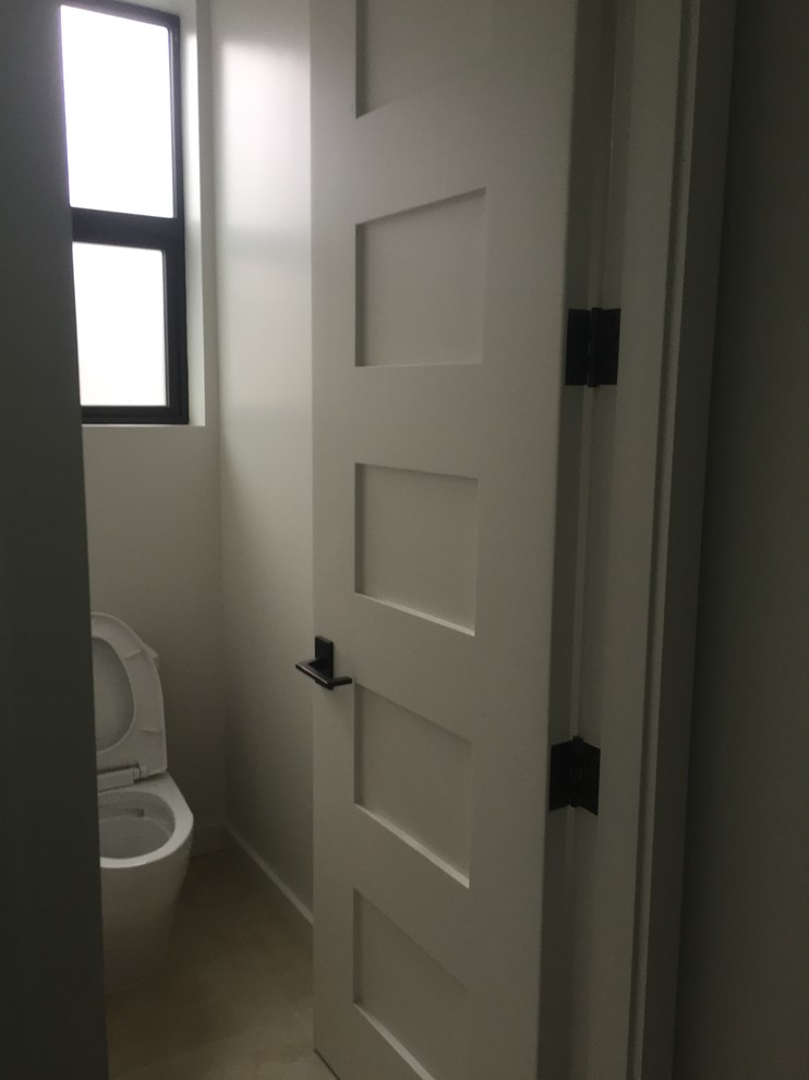Klassisk inredning av ett litet en-suite badrum, med släta luckor, skåp i mörkt trä, en dusch/badkar-kombination, en toalettstol med separat cisternkåpa, beige kakel, stickkakel, vita väggar, marmorgolv, ett undermonterad handfat och marmorbänkskiva