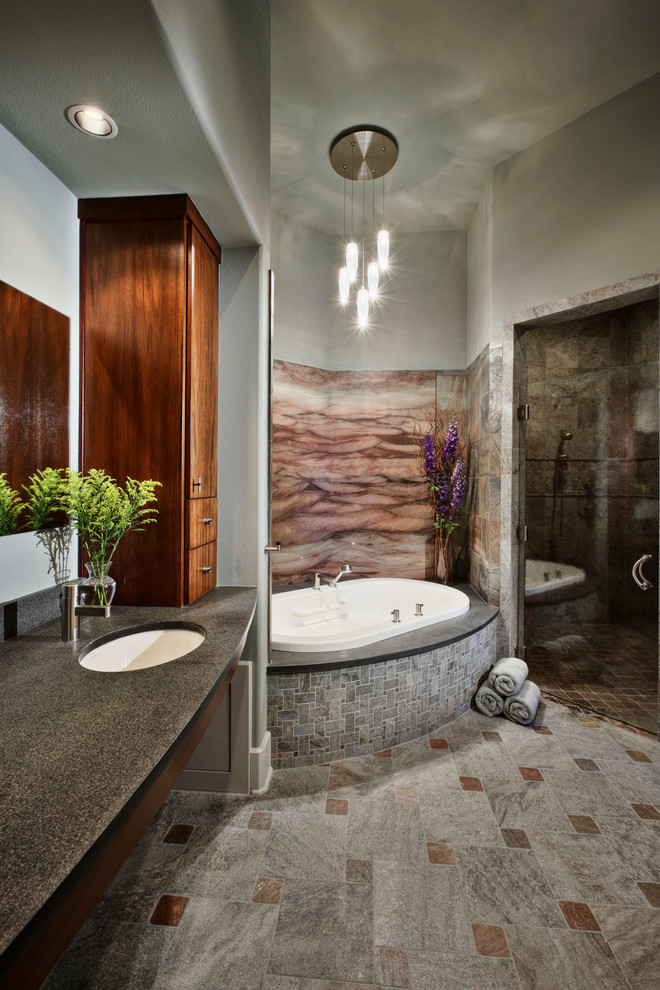 Modernes Badezimmer mit Unterbauwaschbecken, flächenbündigen Schrankfronten, hellbraunen Holzschränken, Unterbauwanne, Duschnische, grauen Fliesen, buntem Boden und grauer Waschtischplatte in Austin