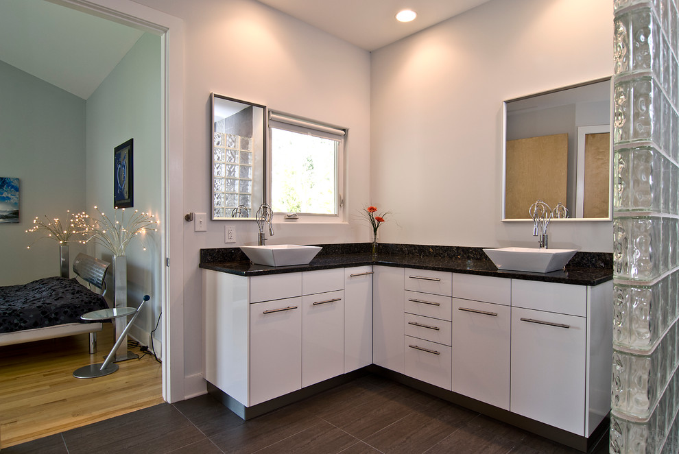 Foto de cuarto de baño actual de tamaño medio con armarios con paneles lisos, puertas de armario blancas, paredes grises, aseo y ducha, lavabo sobreencimera y encimera de granito