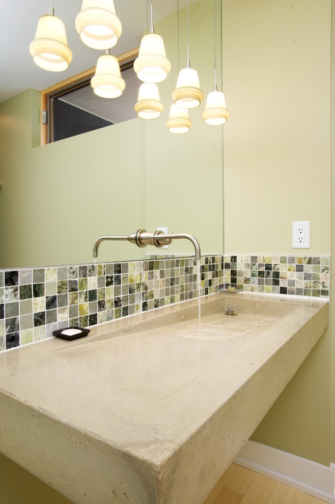 Cette image montre une salle de bain design de taille moyenne avec une grande vasque, un plan de toilette en béton, un carrelage gris, un carrelage en pâte de verre, un mur vert et parquet clair.