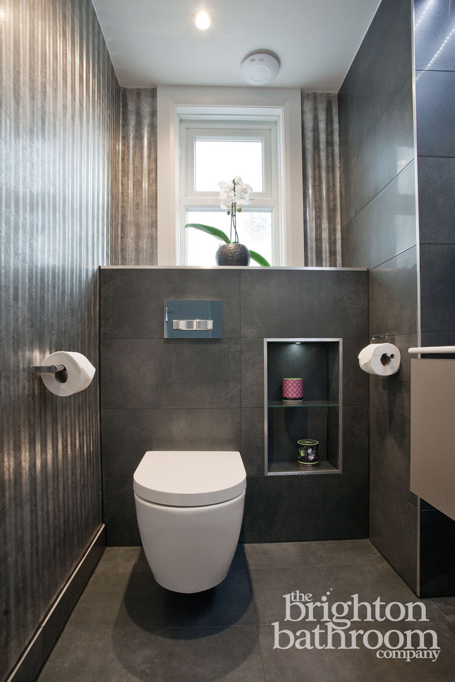 Mittelgroße Moderne Gästetoilette mit verzierten Schränken, grauen Schränken, Toilette mit Aufsatzspülkasten, grauen Fliesen, Porzellanfliesen, grauer Wandfarbe, Porzellan-Bodenfliesen, integriertem Waschbecken und Mineralwerkstoff-Waschtisch in Sussex