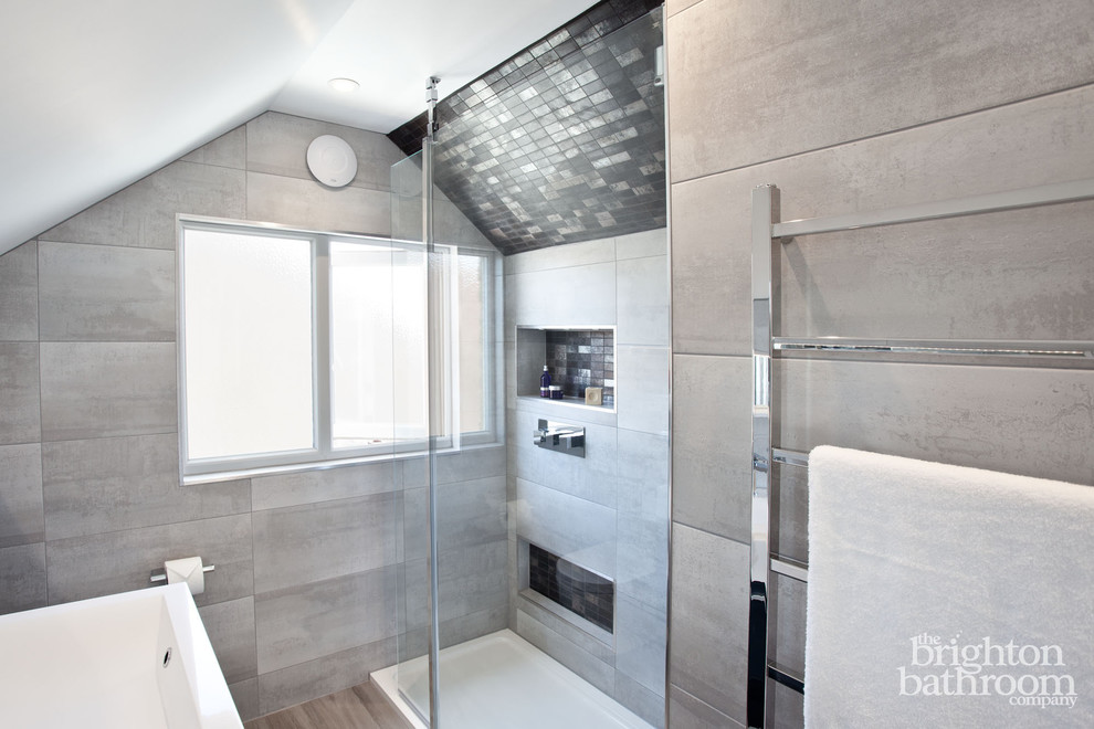 This is an example of a medium sized contemporary ensuite bathroom in Sussex with freestanding cabinets, grey cabinets, a walk-in shower, a one-piece toilet, grey tiles, porcelain tiles, grey walls, porcelain flooring, an integrated sink and solid surface worktops.