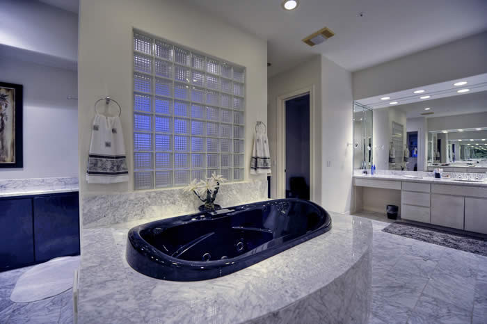 Inredning av ett modernt mycket stort en-suite badrum, med släta luckor, svarta skåp, ett platsbyggt badkar, en kantlös dusch, vit kakel, stenhäll, beige väggar, marmorgolv, ett nedsänkt handfat och marmorbänkskiva