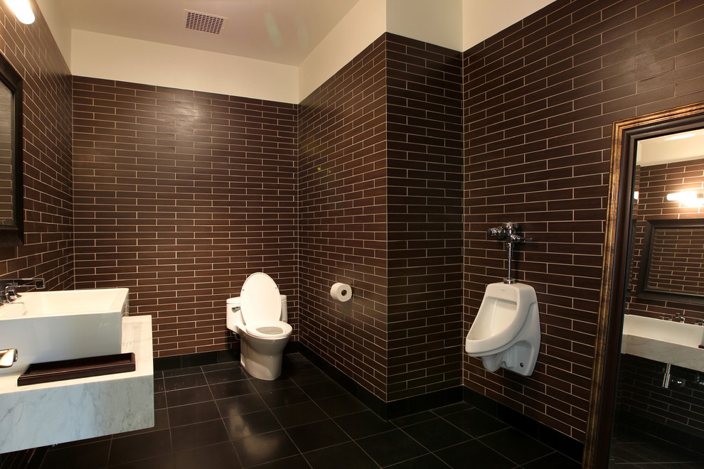 Réalisation d'une très grande salle de bain design avec un placard en trompe-l'oeil, un urinoir, un carrelage marron, des carreaux de céramique, un mur marron, un sol en carrelage de porcelaine, une vasque, un plan de toilette en marbre et un sol noir.