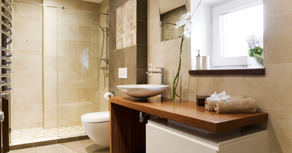 Exempel på ett mellanstort modernt en-suite badrum, med släta luckor, vita skåp, ett platsbyggt badkar, en dusch i en alkov, en vägghängd toalettstol, beige kakel, keramikplattor, beige väggar, klinkergolv i keramik, ett fristående handfat och träbänkskiva