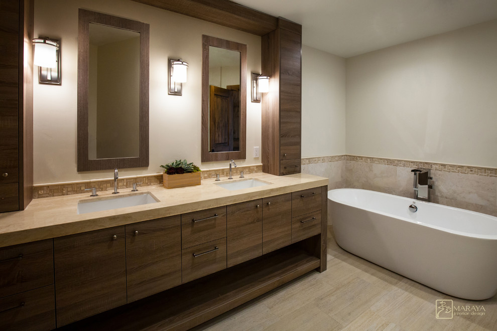 Photo of a medium sized contemporary ensuite bathroom in Santa Barbara with a submerged sink, flat-panel cabinets, medium wood cabinets, limestone worktops, a freestanding bath, an alcove shower, a two-piece toilet, beige tiles, stone slabs, beige walls and marble flooring.