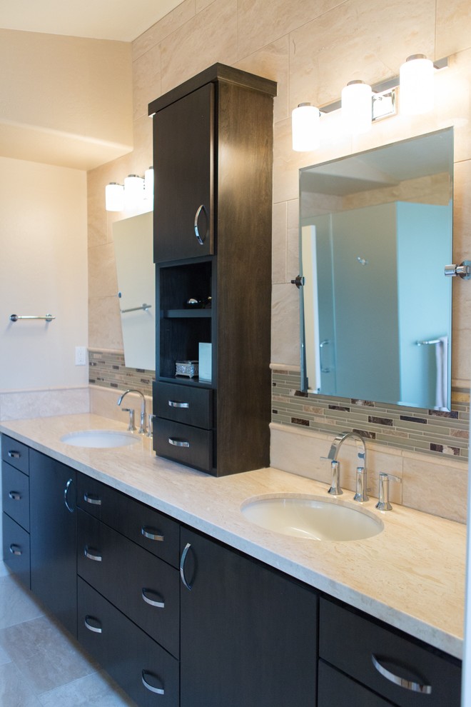 This is an example of a contemporary ensuite bathroom in Phoenix with a submerged sink, flat-panel cabinets, dark wood cabinets, beige tiles and travertine flooring.
