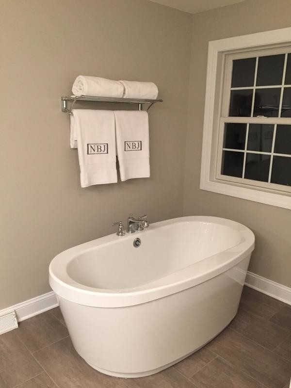 Design ideas for a large contemporary ensuite bathroom in Boston with a submerged sink, recessed-panel cabinets, white cabinets, a freestanding bath, brown walls, medium hardwood flooring, an alcove shower, a two-piece toilet, white tiles and engineered stone worktops.