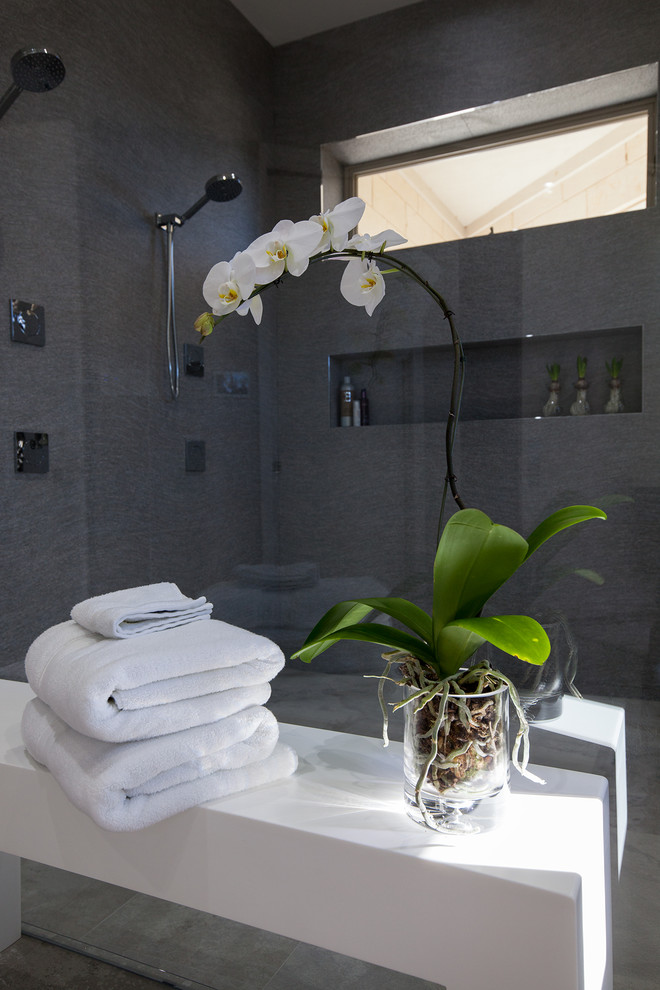Inspiration för ett mellanstort funkis en-suite badrum, med öppna hyllor, grå skåp, ett fristående badkar, en öppen dusch, grå kakel, flerfärgad kakel, spegel istället för kakel, grå väggar, klinkergolv i keramik, ett integrerad handfat och bänkskiva i akrylsten