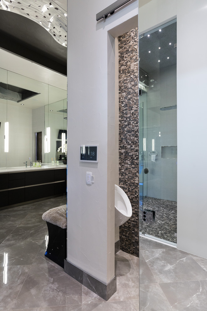 Inredning av ett modernt stort en-suite badrum, med släta luckor, svarta skåp, en hörndusch, ett urinoar, grå kakel, porslinskakel, grå väggar, marmorgolv, ett integrerad handfat, bänkskiva i kvarts, grått golv och dusch med gångjärnsdörr