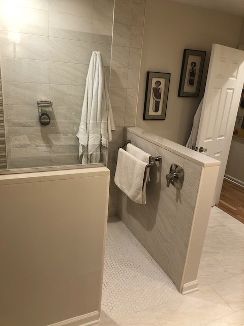 This is an example of a medium sized contemporary ensuite bathroom in Indianapolis with flat-panel cabinets, dark wood cabinets, a corner shower, a two-piece toilet, beige tiles, porcelain tiles, beige walls, porcelain flooring, a vessel sink, solid surface worktops, beige floors and an open shower.