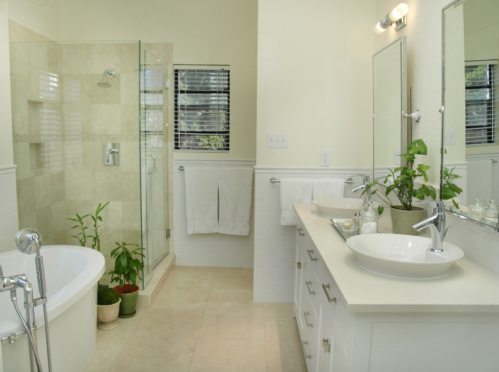 Klassisk inredning av ett mellanstort en-suite badrum, med ett fristående badkar, travertinkakel, skåp i shakerstil, vita skåp, beige kakel, vit kakel, travertin golv, ett fristående handfat, beige väggar och marmorbänkskiva