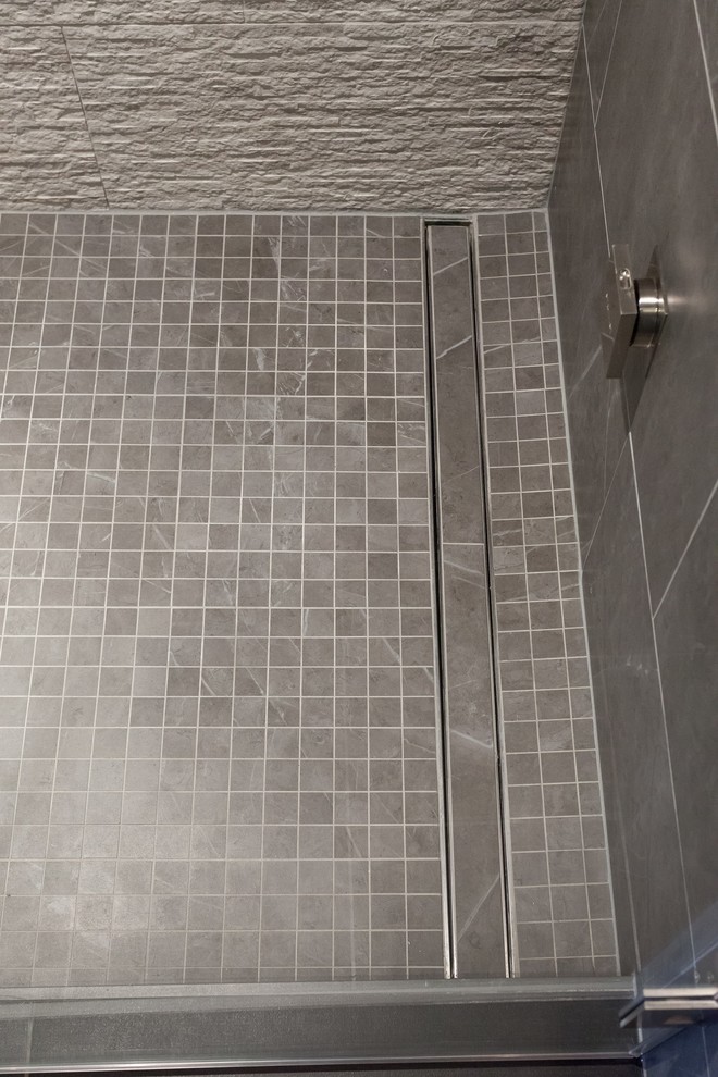 Идея дизайна: главная ванная комната в современном стиле с плоскими фасадами, серыми фасадами, отдельно стоящей ванной, душем в нише, серой плиткой, серыми стенами, настольной раковиной, черным полом, душем с распашными дверями и серой столешницей