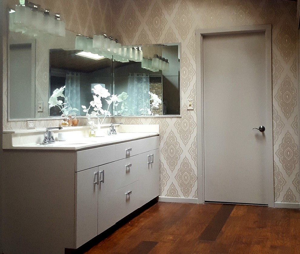 Idées déco pour une petite salle de bain principale contemporaine avec un placard à porte plane, des portes de placard beiges, un mur multicolore, parquet foncé, un lavabo intégré et un plan de toilette en surface solide.