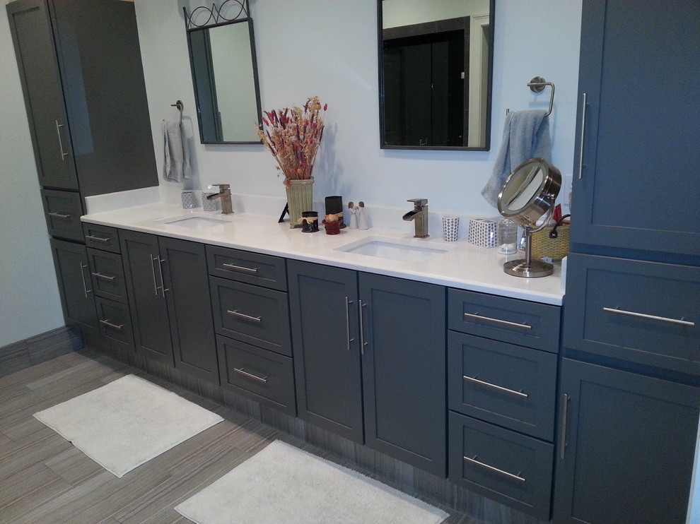Foto de cuarto de baño principal actual de tamaño medio con armarios con paneles lisos, puertas de armario azules, suelo laminado, lavabo integrado, encimera de laminado y suelo beige